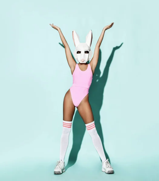 Sexy atletický štíhlé žena modelka v růžové plavky, vysoké ponožky a dekorativní králičí hlava králík maska stojí drží ruce nahoru — Stock fotografie