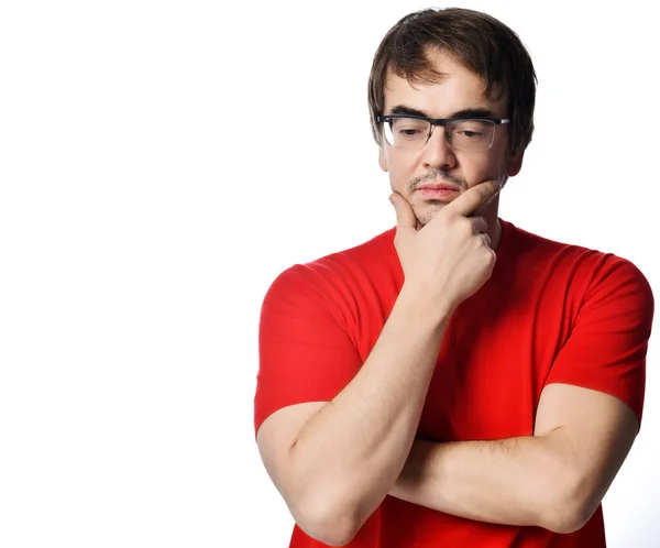 Retrato de hombre sin afeitar pensativo en gafas y camiseta roja tocando la barbilla y pensando en el fondo con espacio para copiar —  Fotos de Stock