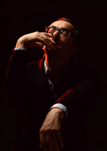 Uomo di mezza età in abito ufficiale e occhiali seduti e fumare sigaretta piacevole tenendo la testa in su e gli occhi chiusi — Foto Stock