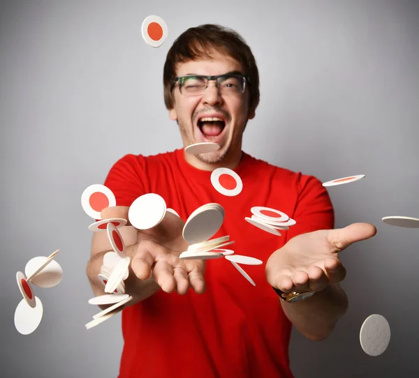 Riendo hombre adulto en camiseta roja y gafas se divierte trotando lanzando redondo blanco con tapetes de cerveza rojos círculos de cartón — Foto de Stock
