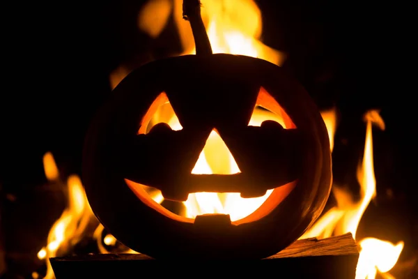 Halloween pumpkin with scary face on fire background.