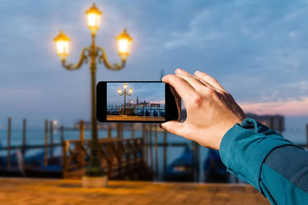 Photographing with smartphone in hand. Venice gondolas on San Marco square