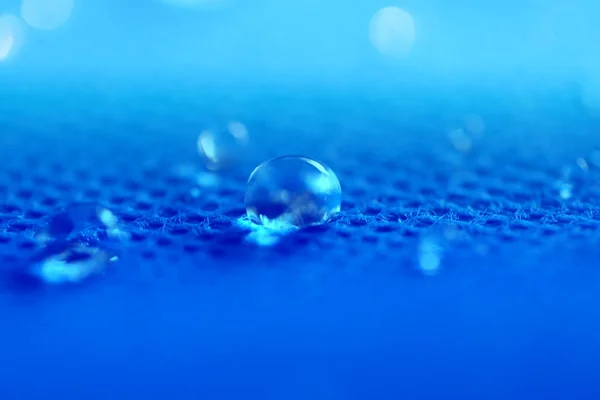 Piękne krople wody fotografowane z bliska na niebieskim tle — Zdjęcie stockowe