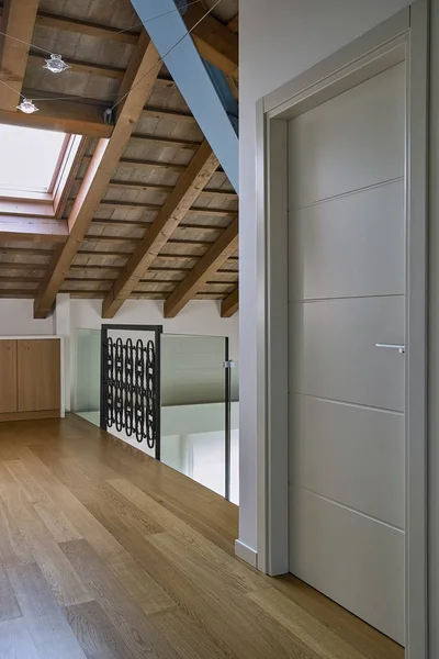 前景漆塗りの白いドア フローリングと木製の梁で屋根裏部屋に現代的な廊下のインテリア ショット — ストック写真
