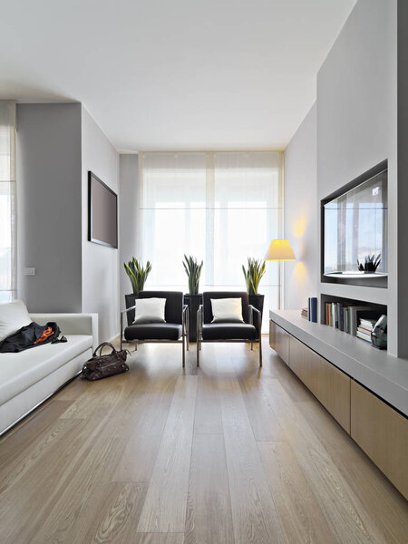 interiors shots of a modern living room in the foreground two leather armchairs and leather sofa the floor is made of wood