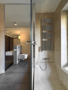 İç çekim ile mozaik kaplı küvet ve duş kabin ön planda modern bir banyo lavabo alt döşer
