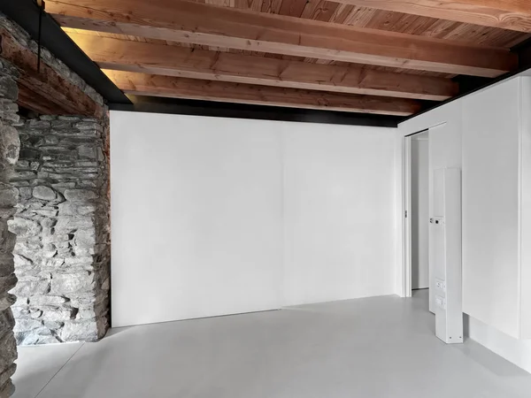 木製の梁天井と樹脂製の床を持つ空の部屋で壁は石で覆われています — ストック写真