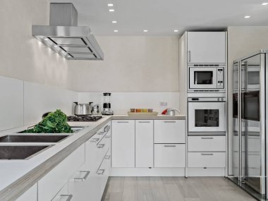 Çelik kapüşonlu, ahşap zeminli modern bir mutfağın iç çekimleri.