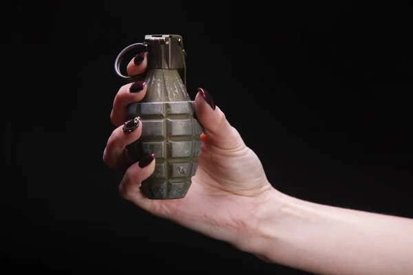 fragmentation grenade in woman hand on black background