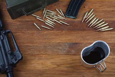 assault rifle and cup of coffee on wooden table background clipart