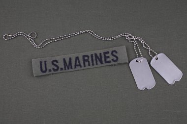 U.S. MARINES Tape with dog tags on olive green uniform background clipart