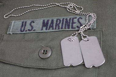 U.S. MARINES Tape with dog tags on olive green uniform background clipart