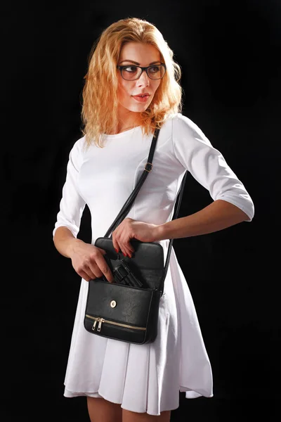 Woman dressed in white with gun on black background