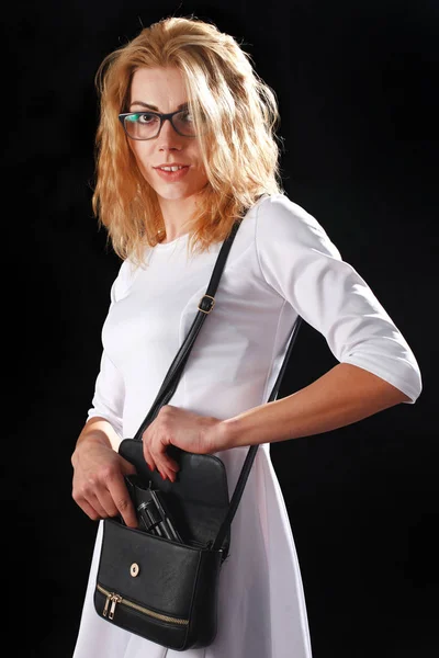 Woman dressed in white with gun on black background