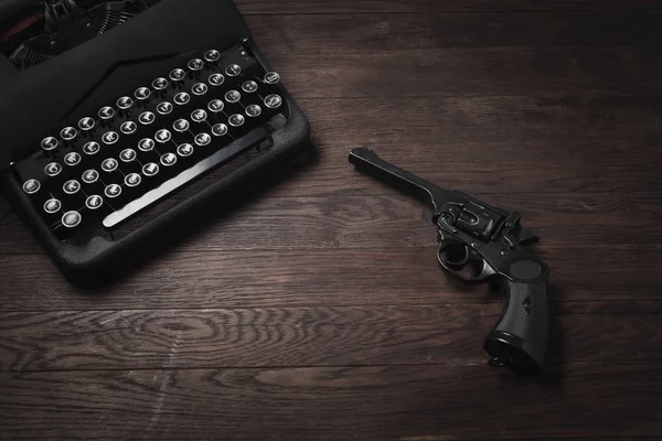犯罪小説 古いレトロなヴィンテージ タイプライターと木製のテーブルにリボルバー拳銃 — ストック写真