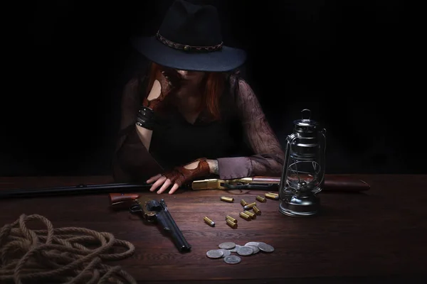 Wild west girl avec revolver gun assis à la table avec des munitions et des pièces d'argent — Photo