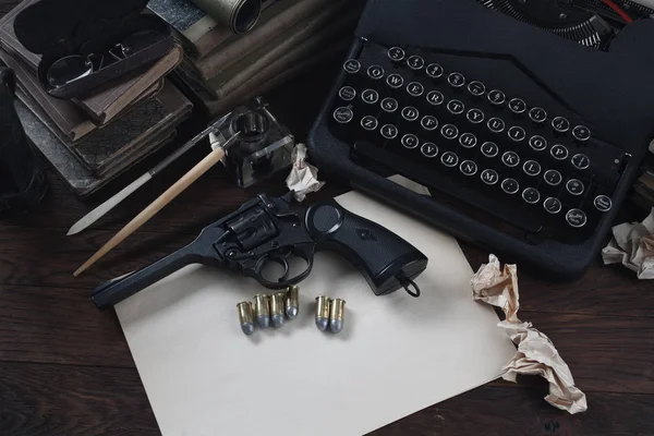 写一个犯罪小说故事- -老式复古打字机和左轮手枪，配有弹药、书籍、空白纸、墨笔 — 图库照片
