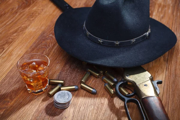 木製のテーブルの上に古い銀ドルとウィスキーと氷のガラスと野生の西ライフルと弾薬 — ストック写真
