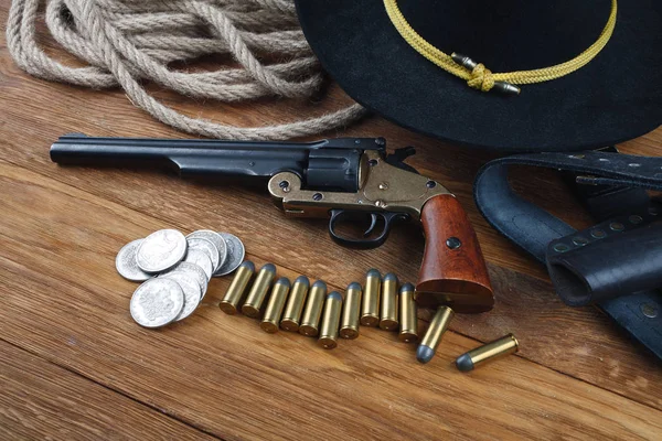 Wild West achtergrond - .44 smid en wesson enkele actie revolver pistool met patronen en zwarte hoed met zilveren dollar munten — Stockfoto