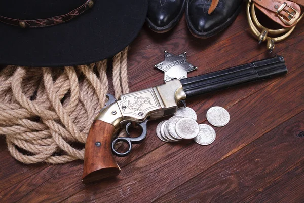 Antiguo revólver occidental con insignia de sheriff y dólares de plata con sombrero, cuerda y botas — Foto de Stock