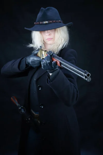 野的西部金发姑娘头戴黑色帽子 枪托着黑色背景的步枪 — 图库照片