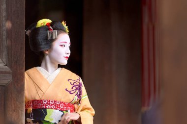 Kyoto, Japonya - 28 Kasım 2015: Geleneksel Maiko elbise görünüyor bir tapınak kapı dan bir kadında.