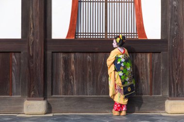 Kyoto, Japonya - 28 Kasım 2015: Geleneksel Maiko elbise görünüyor bir tapınak kapı dan bir kadında.