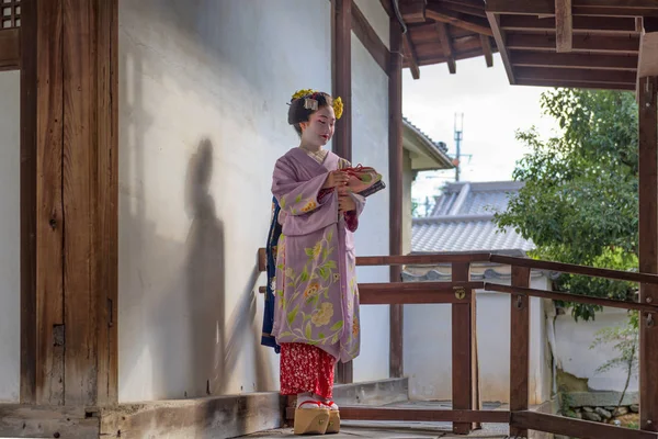 Kyoto, Japonya - 28 Kasım 2015: Geleneksel Maiko elbise görünüyor bir tapınak kapı dan bir kadında.