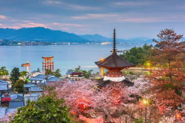 Miyajima Island, Hiroşima, Japonya tapınaklar bahar sezonu alacakaranlıkta Seto İç Denizi ile.