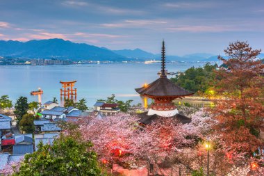 Miyajima Island, Hiroshima, Japan with temples on the Seto Inland Sea at dusk in the spring season. clipart