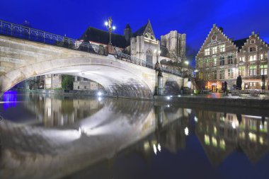 Gent, Belçika 'nın eski şehir manzarası. Geceleri Leie Nehri üzerinde St. Michael Kilisesi ve köprüsü olan..