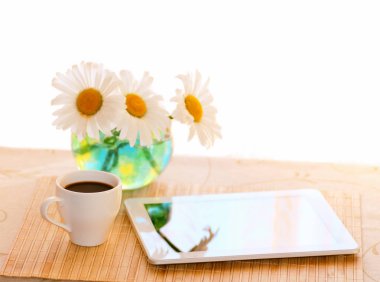 buket papatyalar tablo, kahvaltı kahve ile ve bir tablet, parlak bir ışık sabah ile