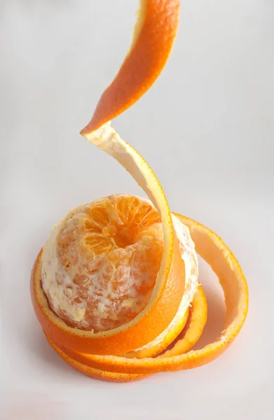 Кольца апельсиновой кожуры свисающие вниз, на сером фоне, спиральная кожура , — стоковое фото