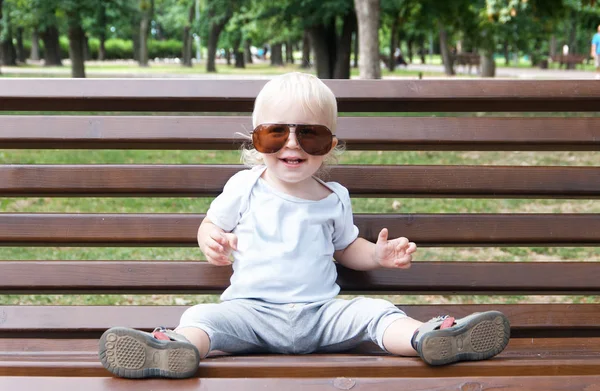 Sitting child with sun glasses, blondidan with blue eyes on a wo — Stock Photo, Image