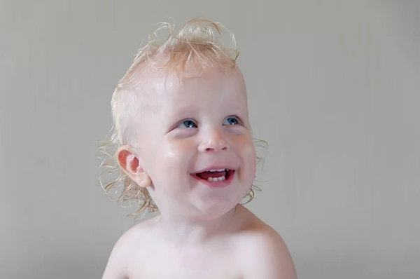 Retrato de risa de un niño con el pelo blanco y ojos azules en un gr —  Fotos de Stock