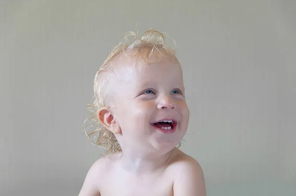 Retrato rindo de uma criança com cabelos brancos e olhos azuis em um gr — Fotografia de Stock