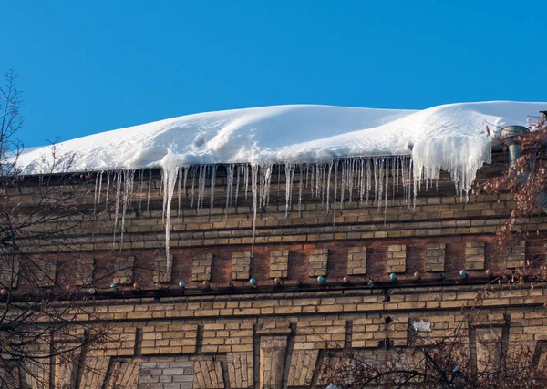 Sople na dachu zimą, stary murowany budynek — Zdjęcie stockowe