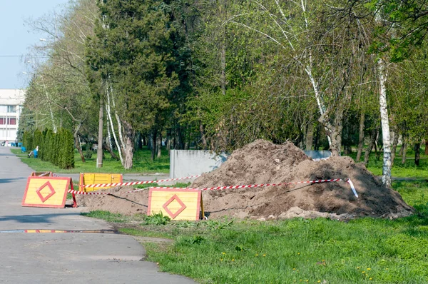 Строительные работы, вырытая яма с предупреждающим знаком в парке — стоковое фото