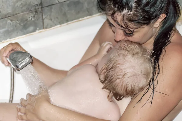 Mãe toma banho com o bebê no banheiro, dirige o chuveiro — Fotografia de Stock