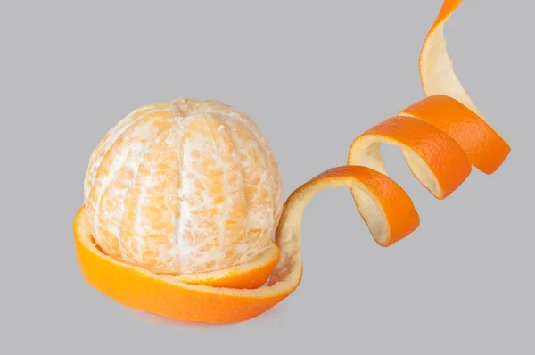 Casca de uma espiral de laranja, cor-de-laranja descascada, visão lateral em um bac cinza — Fotografia de Stock