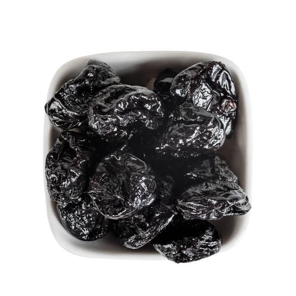 Prunes in a white bowl top view isolated on a white background — 스톡 사진