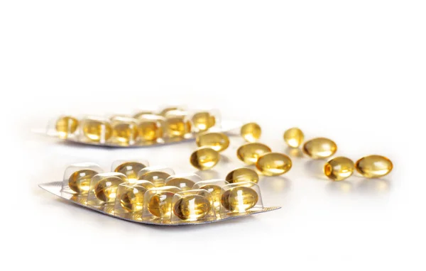 yellow transparent capsules in packaging and in bulk, omega 3 vitamins, isolated on white background