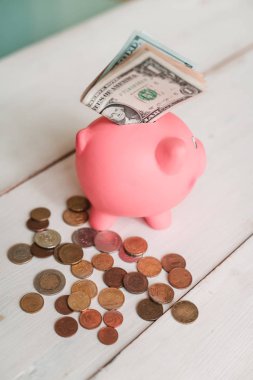 Küçük şirin pembe domuz kumbara ahşap bir masa üzerinde. Üç yığın, sent ve kağıt dolar. Tasarruf ve finans.