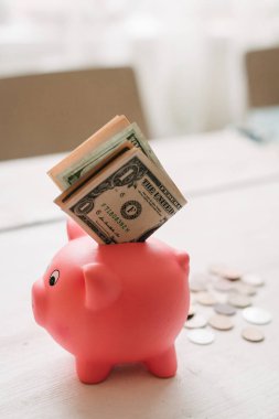 Küçük şirin pembe domuz kumbara ahşap bir masa üzerinde. Üç yığın, sent ve kağıt dolar. Tasarruf ve finans.