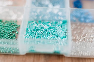 renkli boncuklar ahşap bir masa üzerinde şeffaf plastik kutular