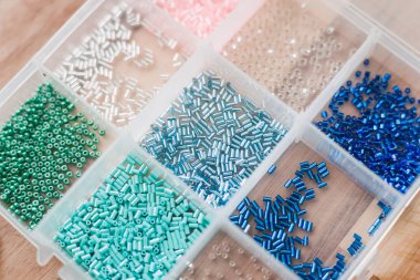 renkli boncuklar ahşap bir masa üzerinde şeffaf plastik kutular