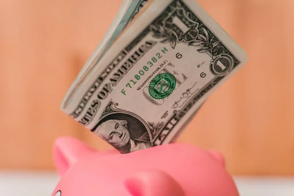 Küçük şirin pembe domuz kumbara ahşap bir masa üzerinde. Üç yığın, sent ve kağıt dolar. Tasarruf ve finans.