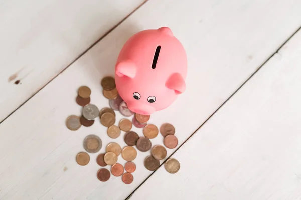 Küçük şirin pembe domuz kumbara ahşap bir masa üzerinde. Üç yığın, sent ve kağıt dolar. Tasarruf ve finans.