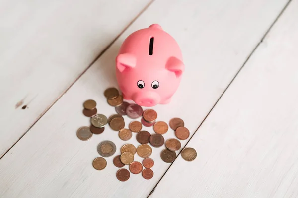 Küçük şirin pembe domuz kumbara ahşap bir masa üzerinde. Üç yığın, sent ve kağıt dolar. Tasarruf ve finans.