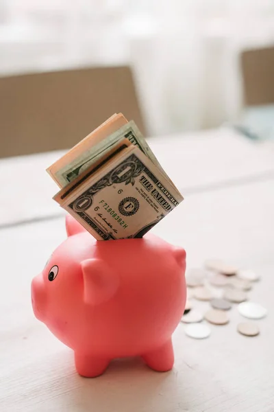 Küçük şirin pembe domuz kumbara ahşap bir masa üzerinde. Üç yığın, sent ve kağıt dolar. Tasarruf ve finans.